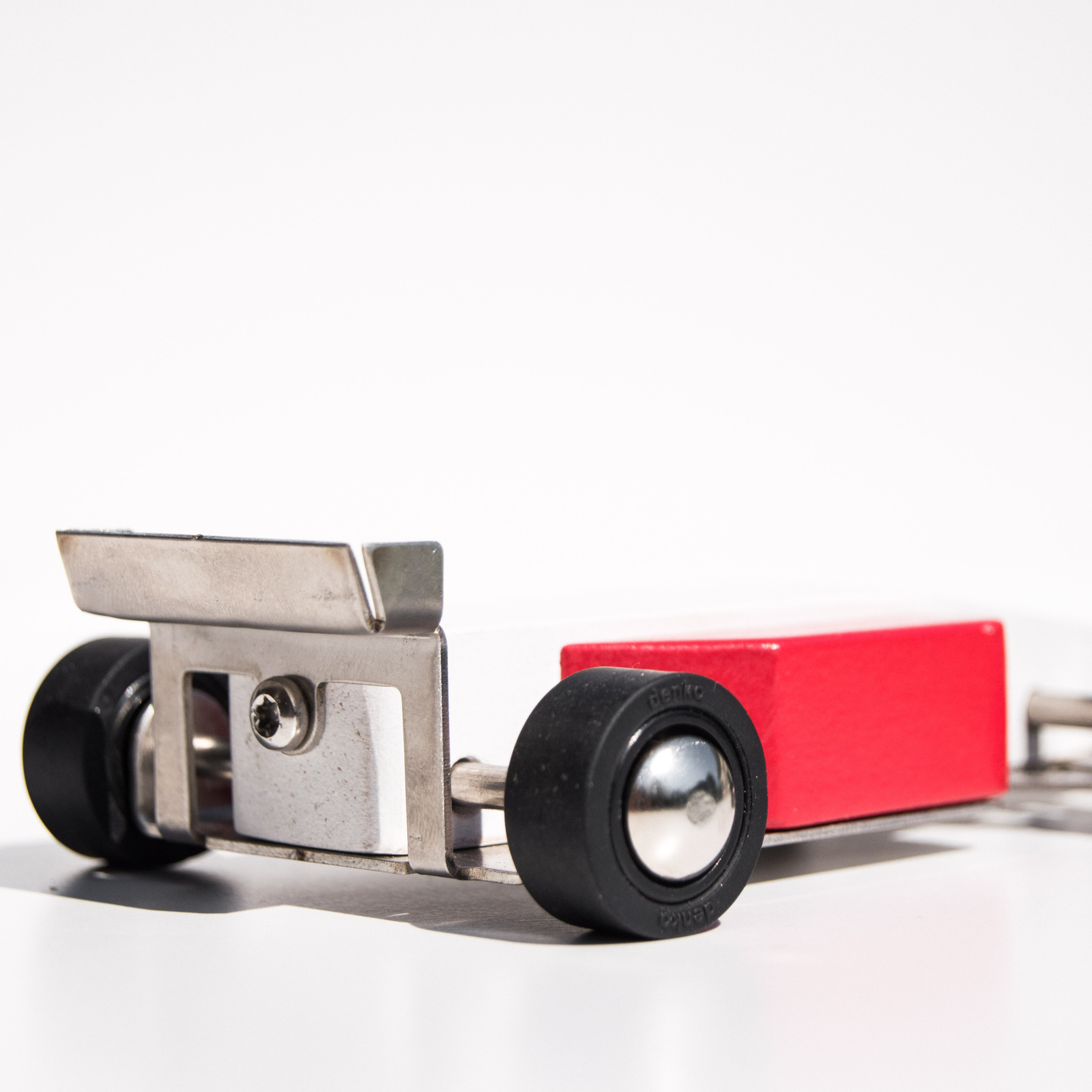 Small model car with red body and black wheels on a white background