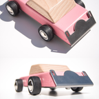 Pink wooden toy car features on a white background
