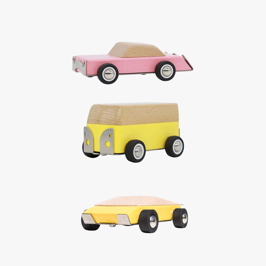 Three wooden toy cars in pink, yellow, and blue on a white background