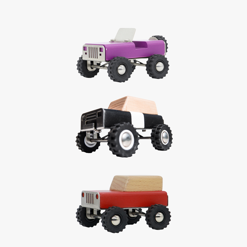 Three wooden monster trucks in purple, black, and red on a white background
