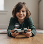 Child holding a toy car with 'Arrow' branding on a wooden floor.