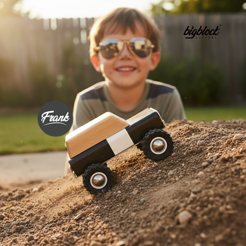 Child wearing sunglasses with a wooden toy truck in the foreground, blurred background