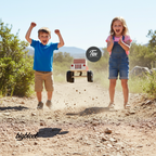 Two children on a dirt road with a wooden toy truck labeled 'Tex' in the center.