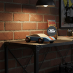 Toy car on a metal surface with a brick wall background and 'Miles' logo.