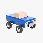 Wooden toy truck with blue body and beige bed on a white background