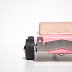 Close-up of a wooden toy car with pink color and black wheels on a white background