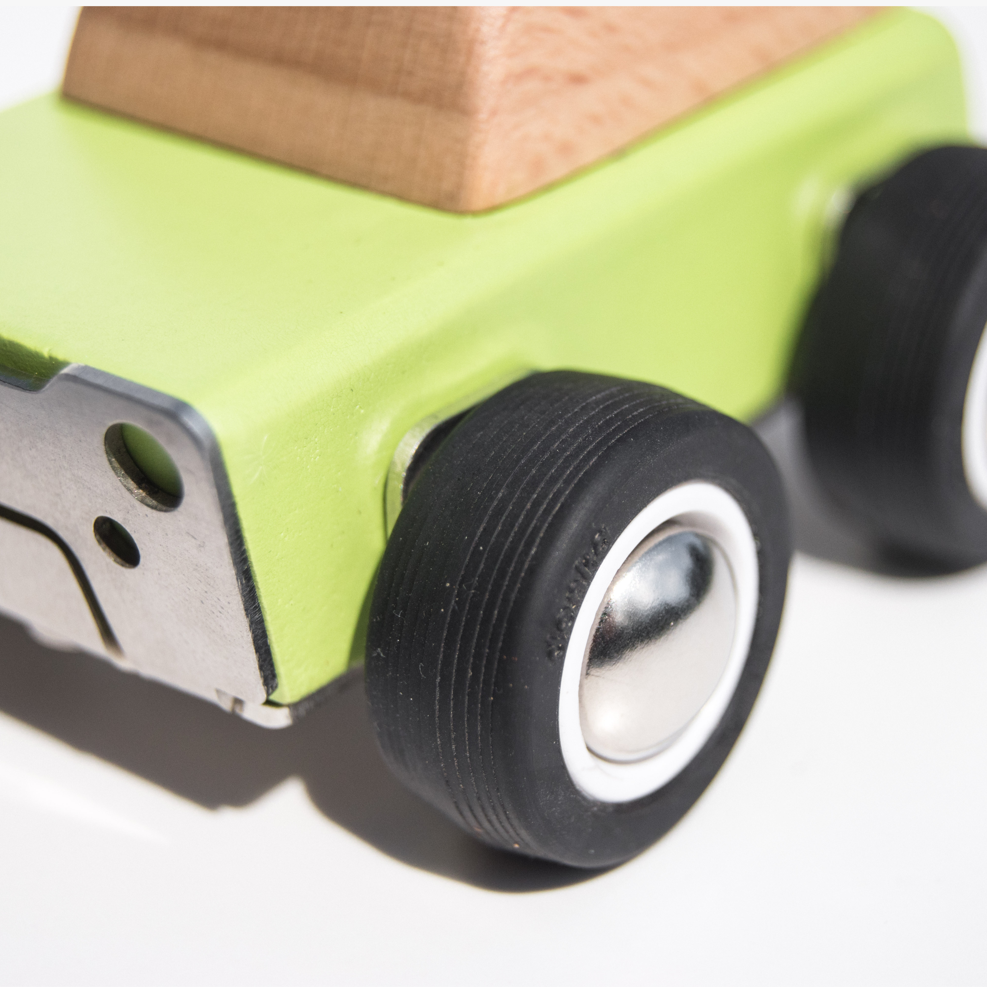 Close-up of a green wooden toy car with black wheels on a white background