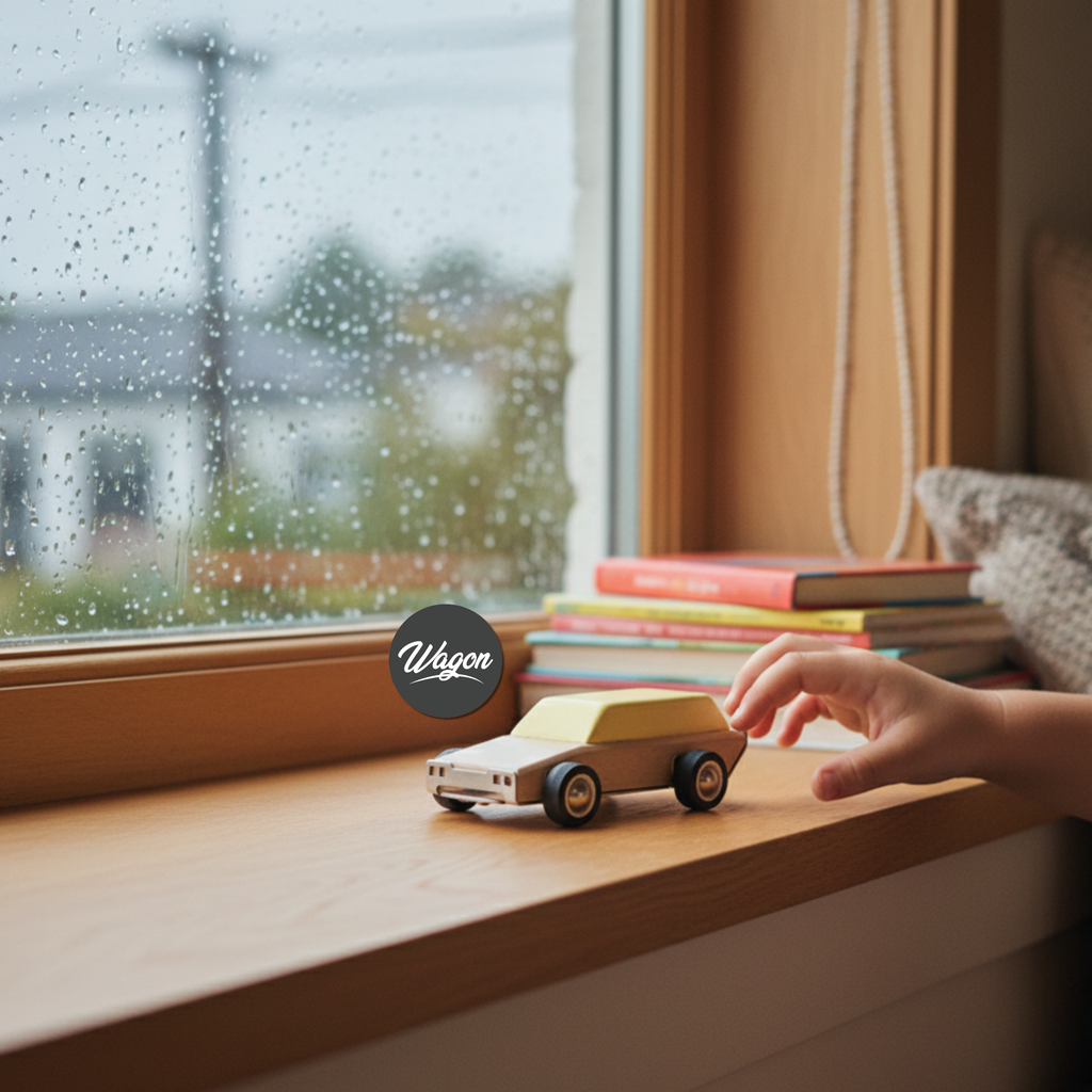 Hand playing with a toy car on a windowsill with a rainy day outside